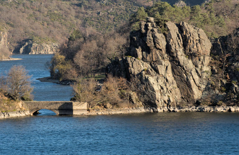 Gorges de la loir avec un petit pont en pierre traversant un bras reliant deux zones rocheuses