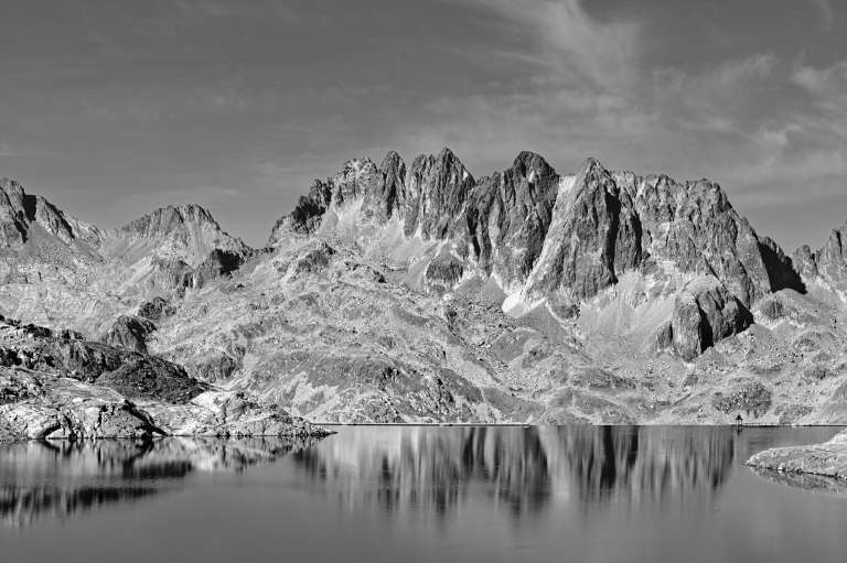 Photo noire et blanc d’un lac de l’Étandard avec en reflets des montagnes en arrière plan